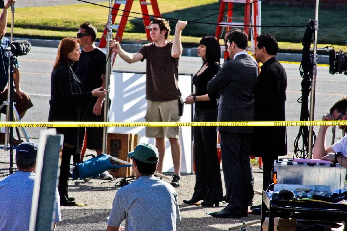 A film crew and actors at work outdoors beside equipment