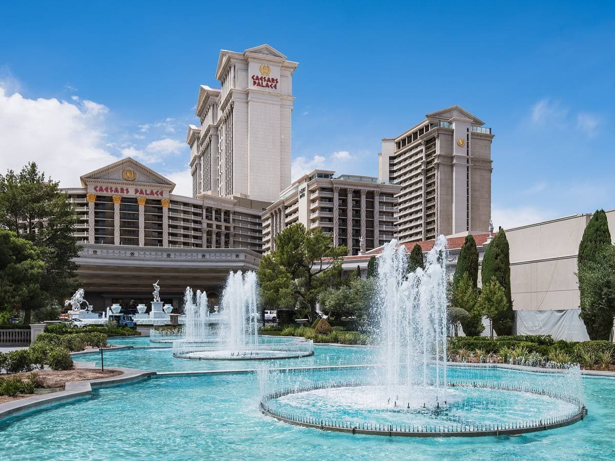 A large white hotel tower behind fountains and gardens