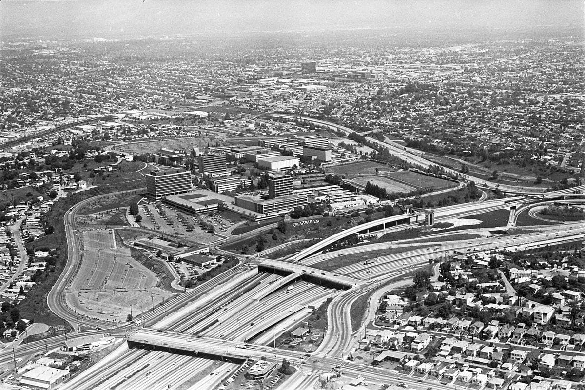 An aerial view of a hillside university campus among freeways