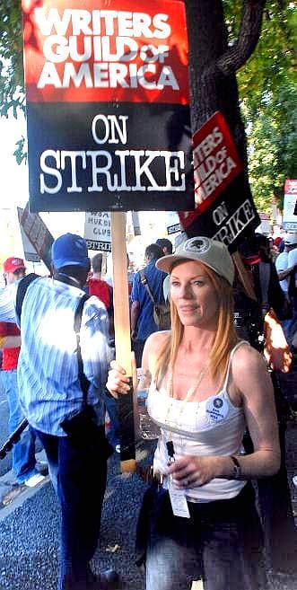 A woman with long red hair in sunglasses on a picket line