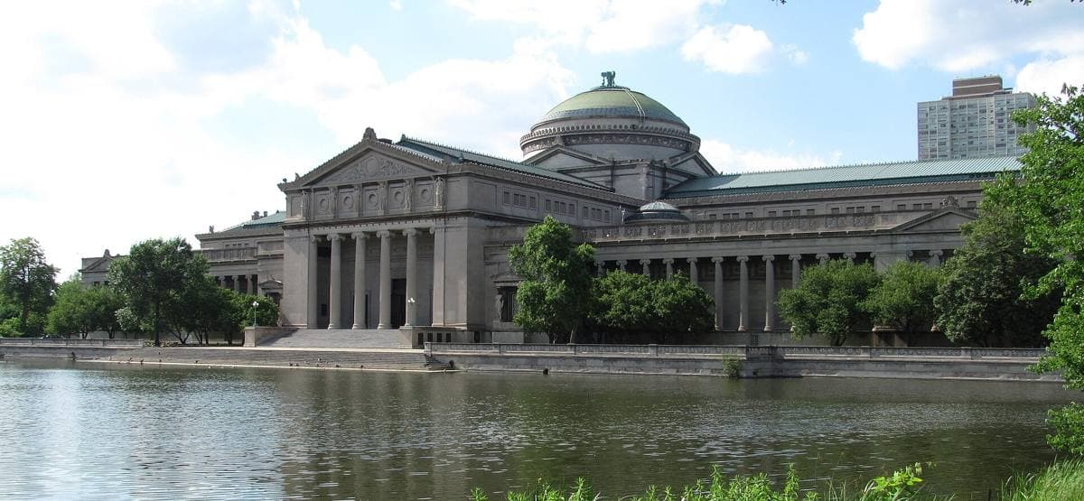 A long classical museum with a central dome above a lagoon
