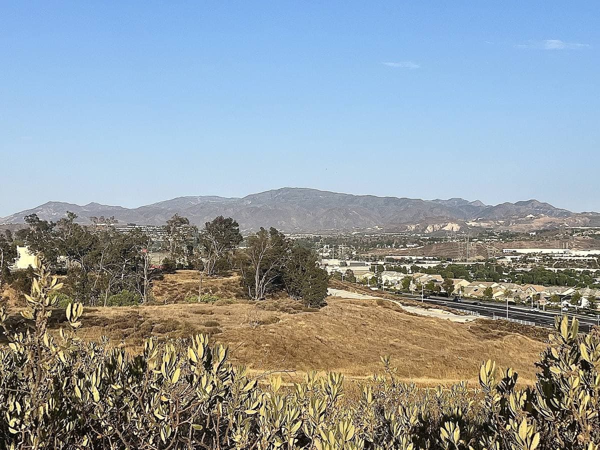 Brown chaparral hills under a blue sky beyond a park