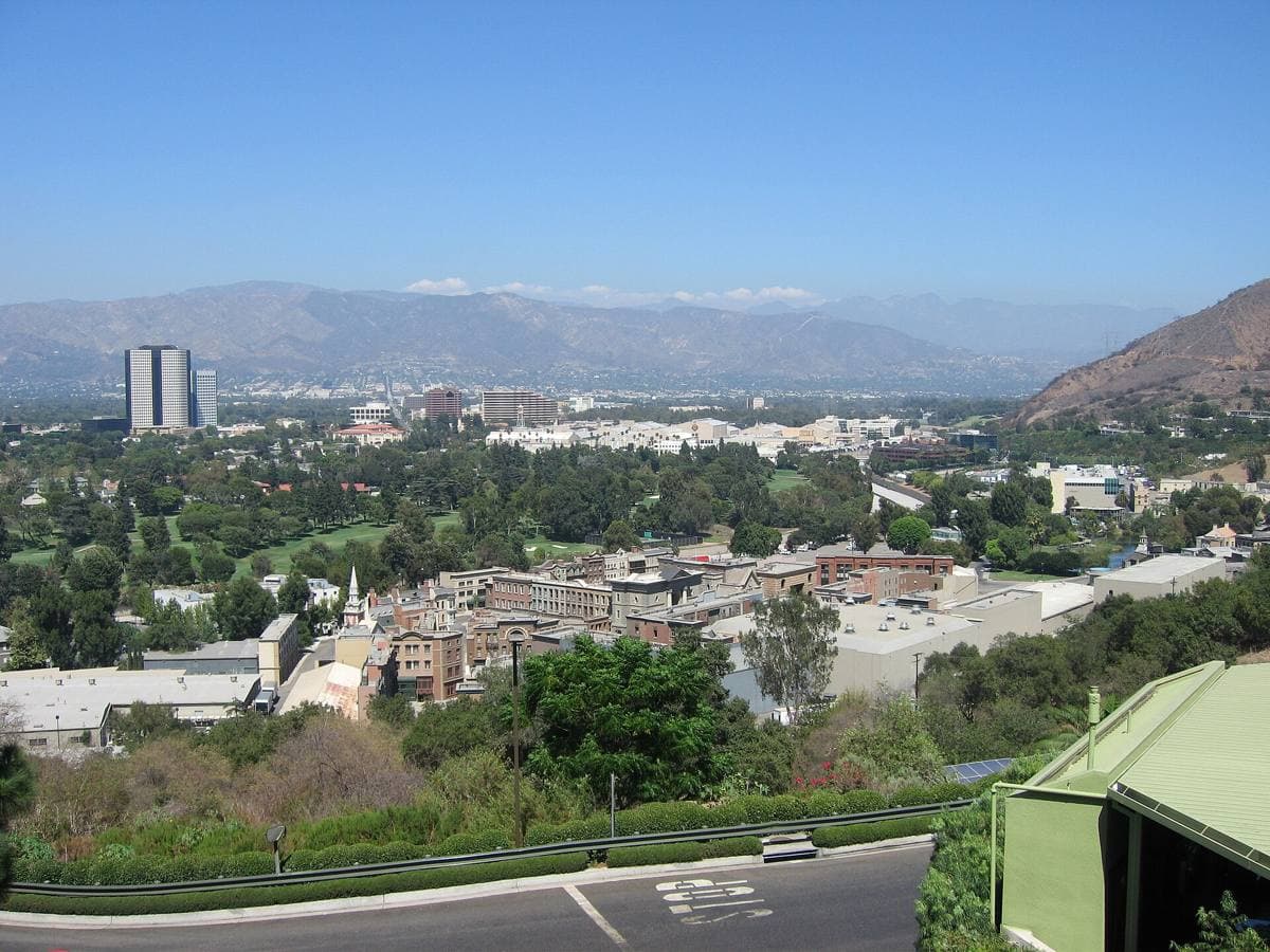 Rows of studio sound stages and backlot streets with mountains behind
