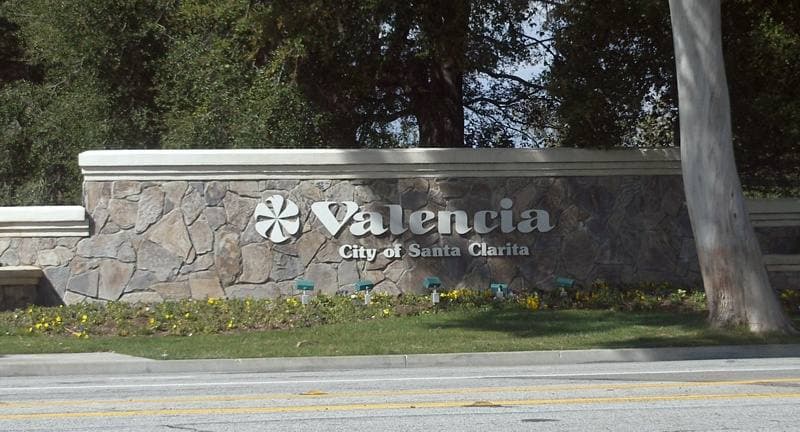 A low stone sign reading Valencia beside a landscaped road