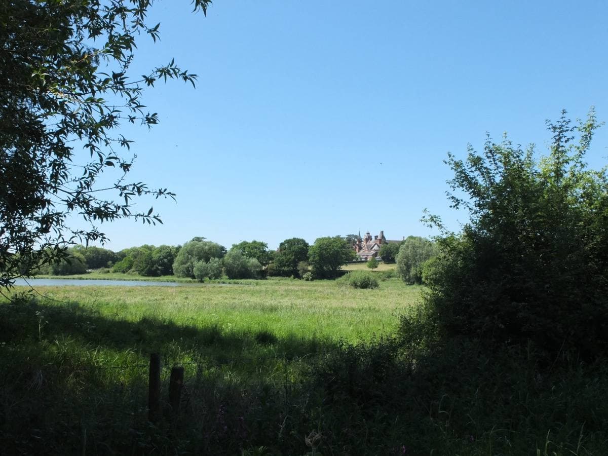 A large Victorian red-brick school building on a rise above green fields