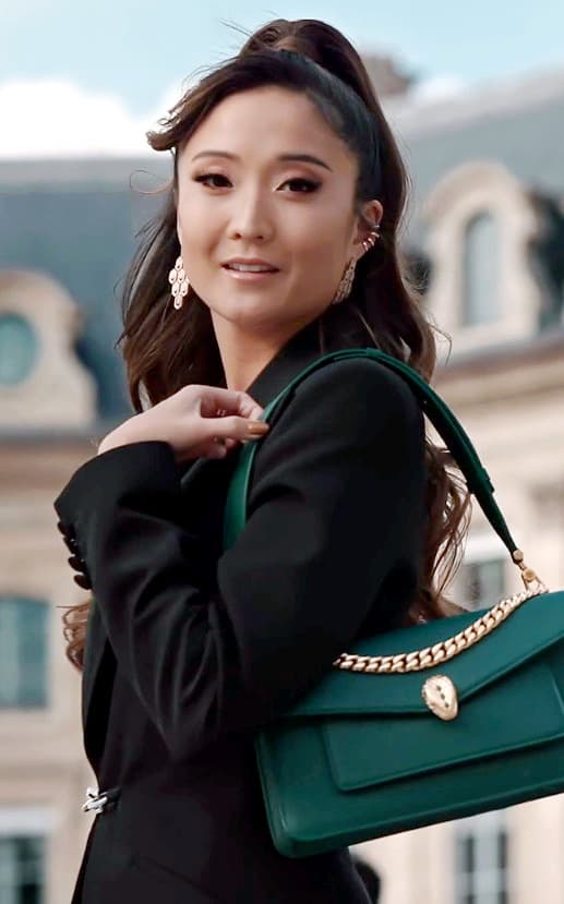 Ashley Park in a black blazer, long dark hair, holding a green leather handbag