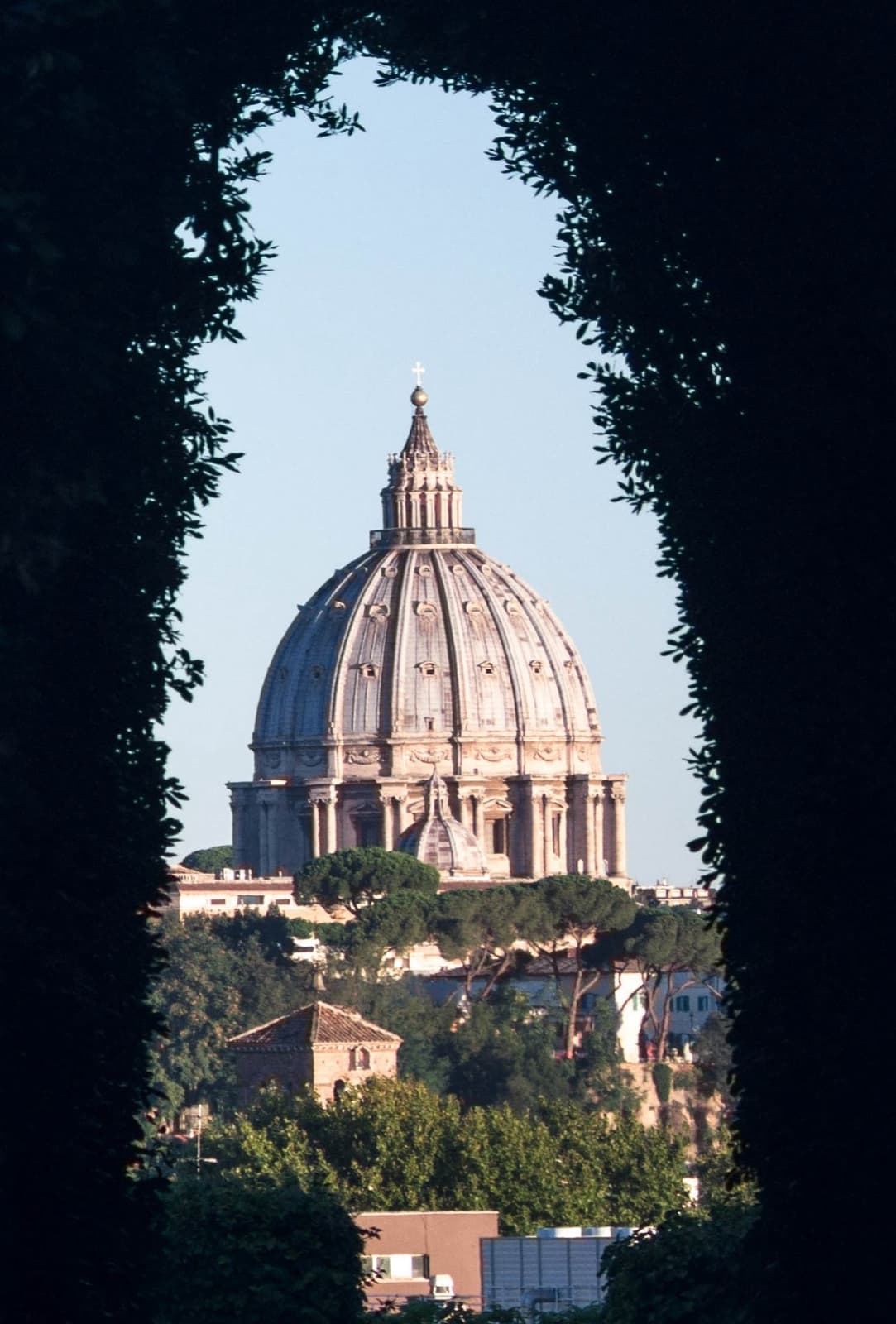 The dome of St Peter’s framed at the end of a dark tunnel of clipped hedges, seen through a keyhole