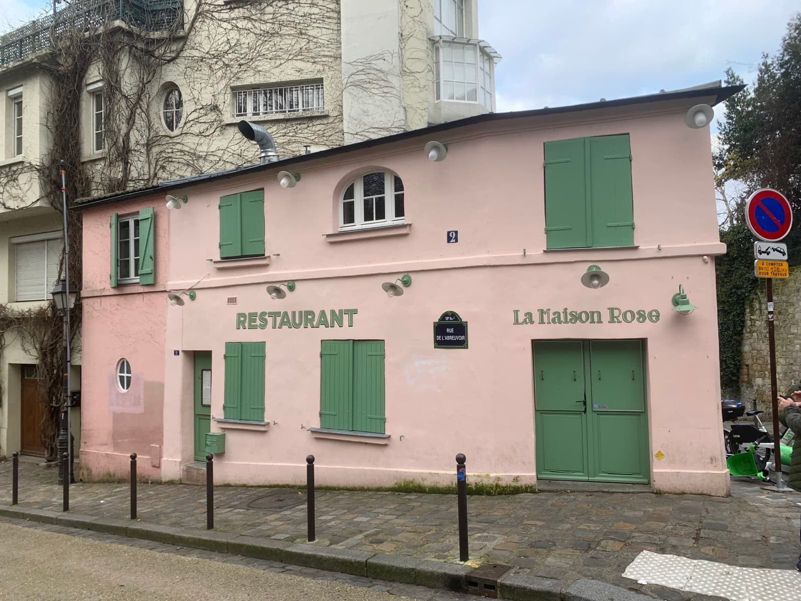 A small pink house with green shutters on a sloping Montmartre corner, Restaurant painted on the wall