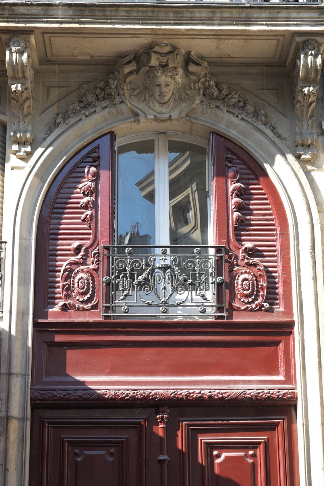 A red-painted restaurant front with red awning beneath cream stone apartments