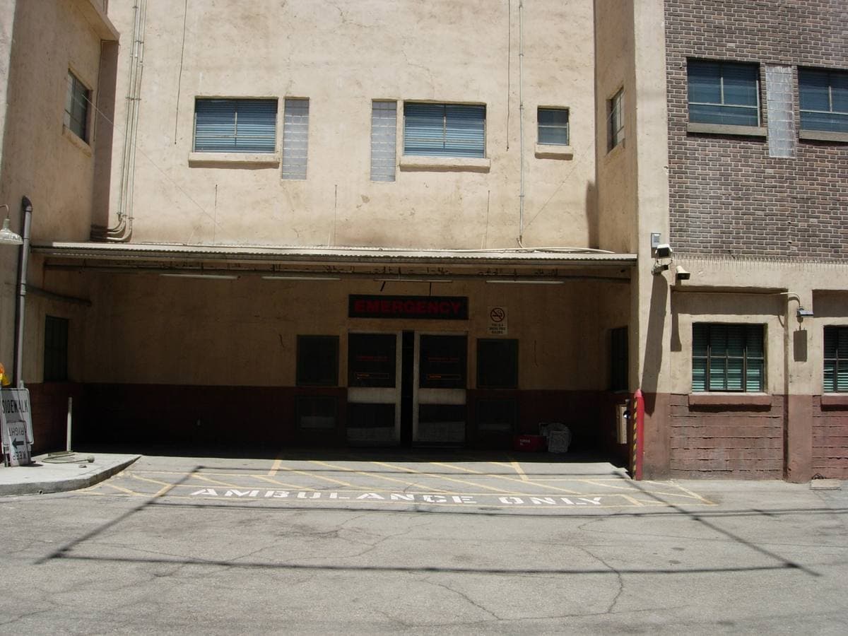 A plain studio facade with a canopied entrance and AMBULANCE ONLY painted on the tarmac