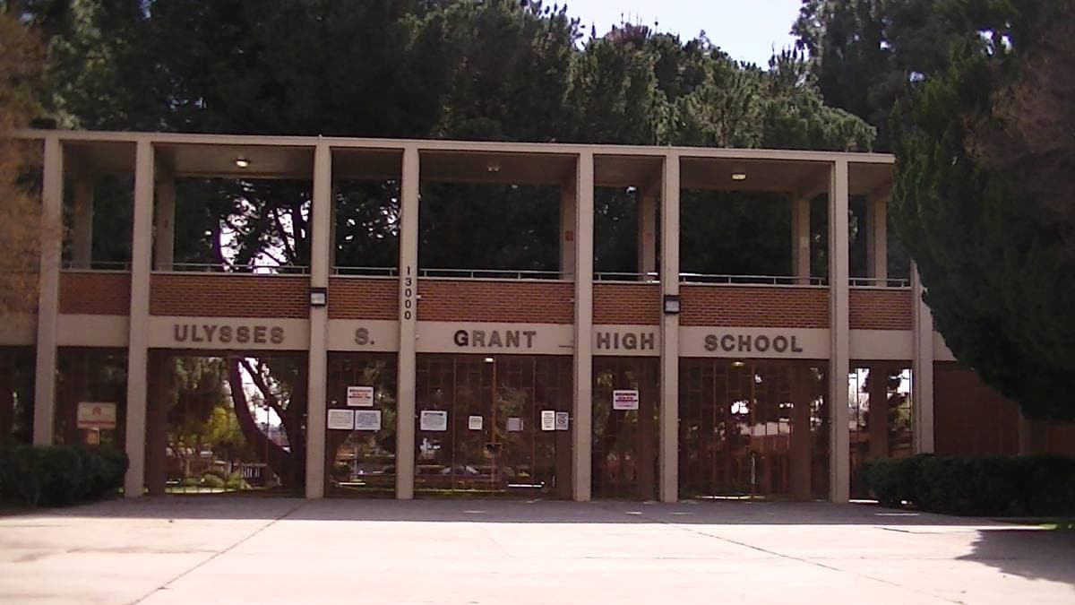 The low front of a 1950s school building with lawn and trees