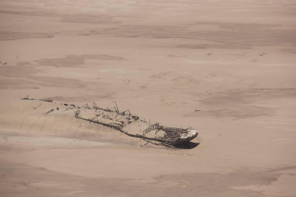 A rusted shipwreck lying in desert sand
