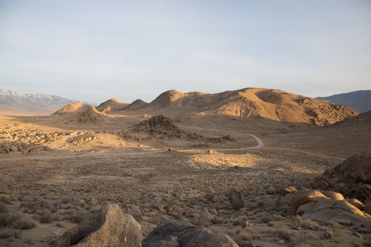 Rounded boulders on a desert flat below the snow-capped Sierra Nevada