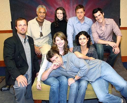 Eight members of the Firefly cast sitting and standing together on a convention stage