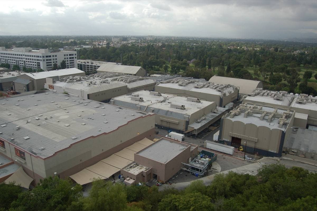 Rows of large beige soundstages on a hillside studio lot