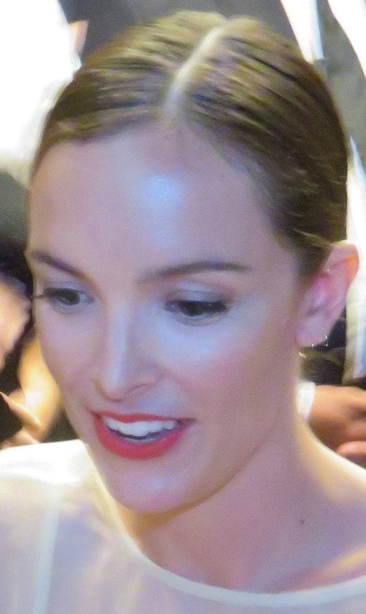 A woman with short fair hair smiling at a premiere