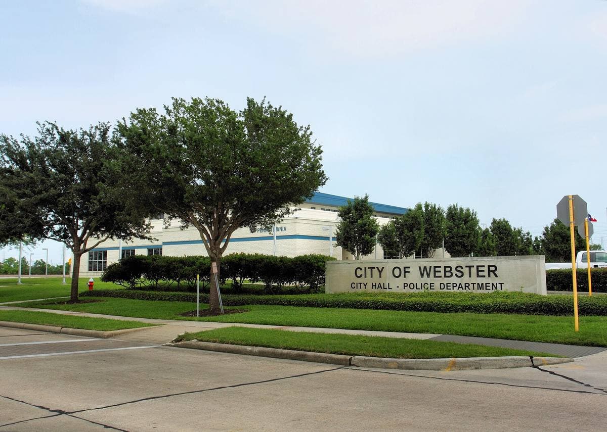 A low brick civic building with a flagpole in Webster, Texas