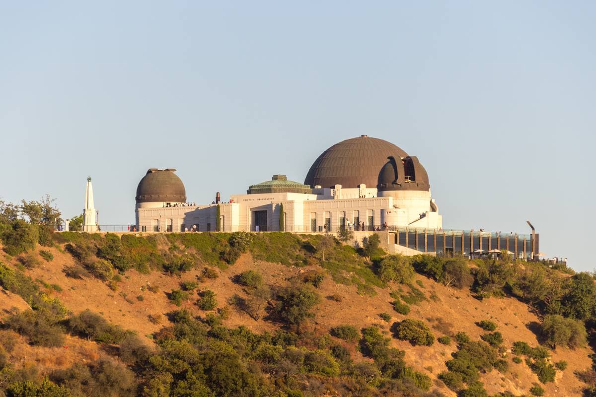 A white Art Deco observatory with three domes on a hill