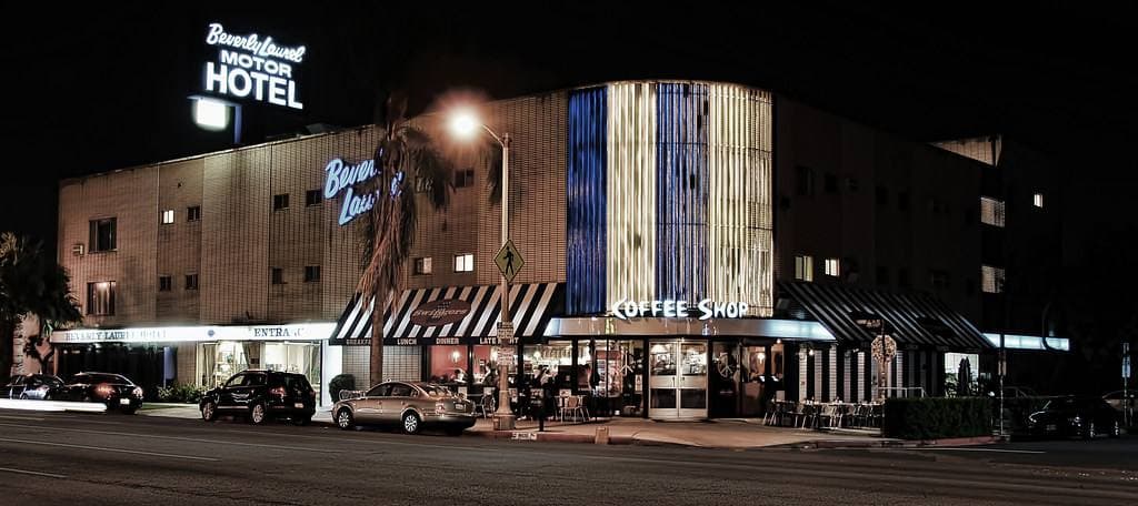 A diner sign and a motel front lit up at night
