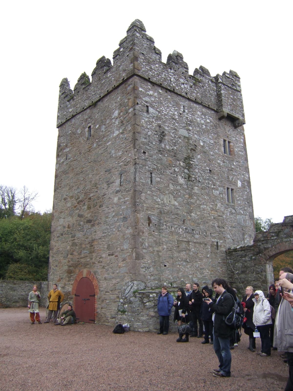 A stone tower house in a farmyard with visitors