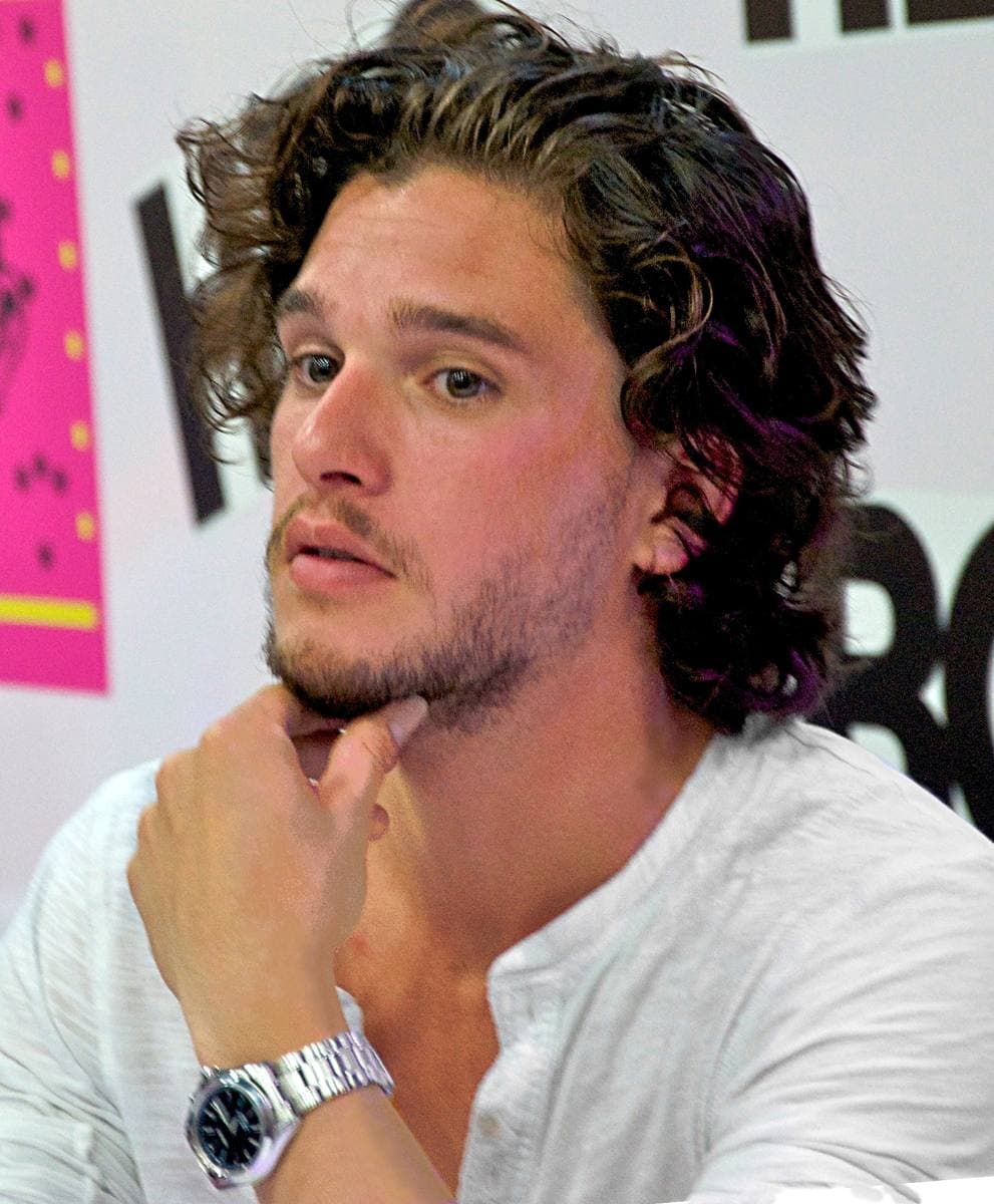 Kit Harington with long curly hair, chin on hand