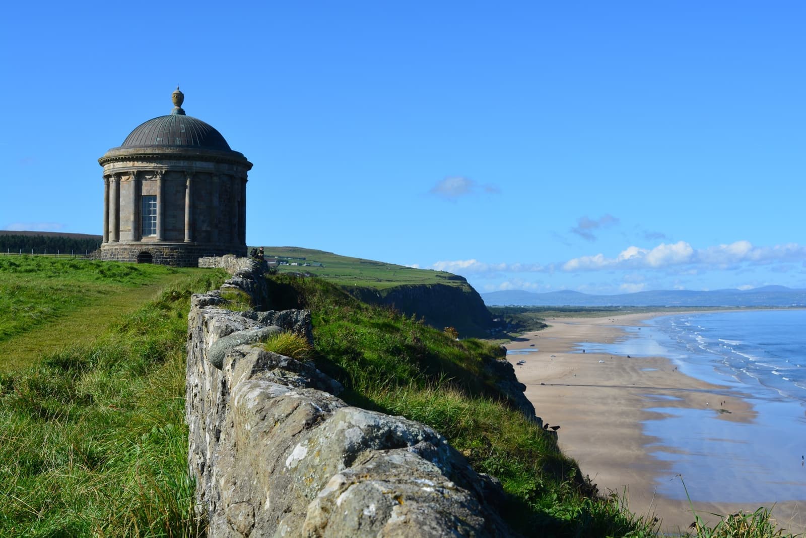 A small domed temple on a cliff above a long beach