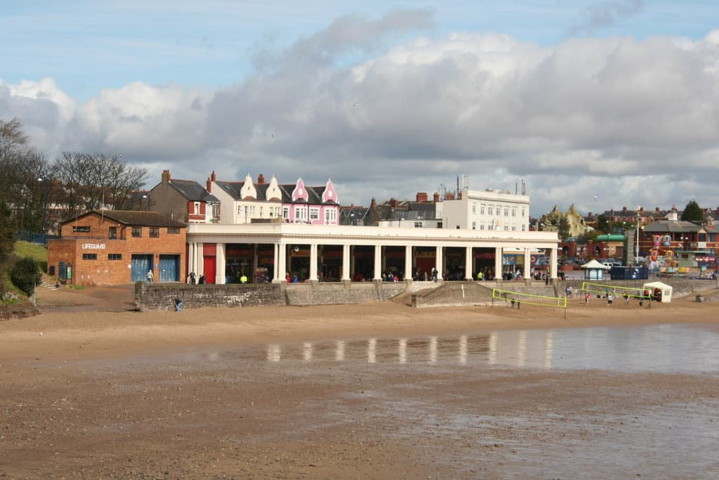A long white colonnade of seafront arcades seen across wet sand