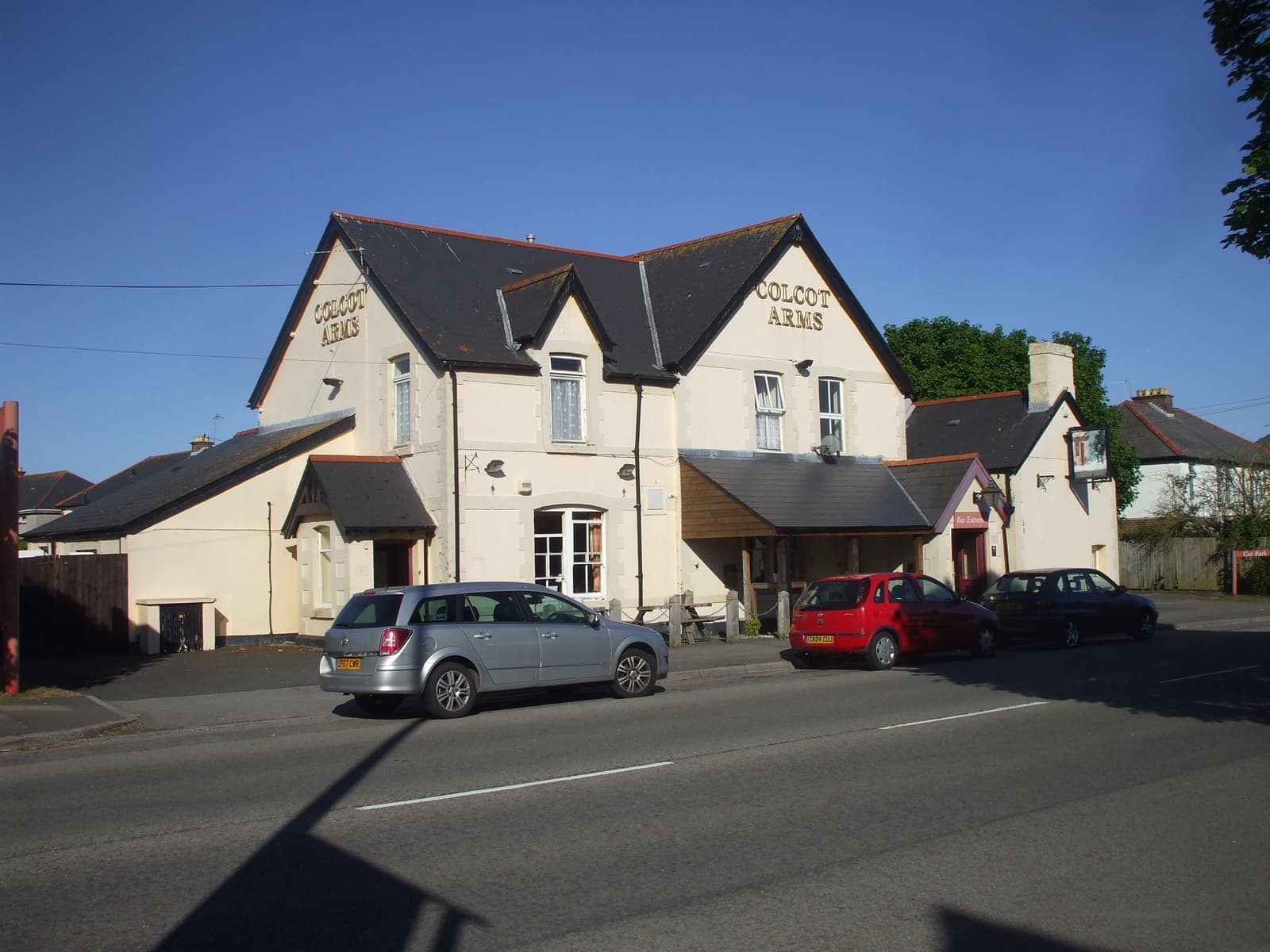 A cream-painted pub with steep gables and cars outside
