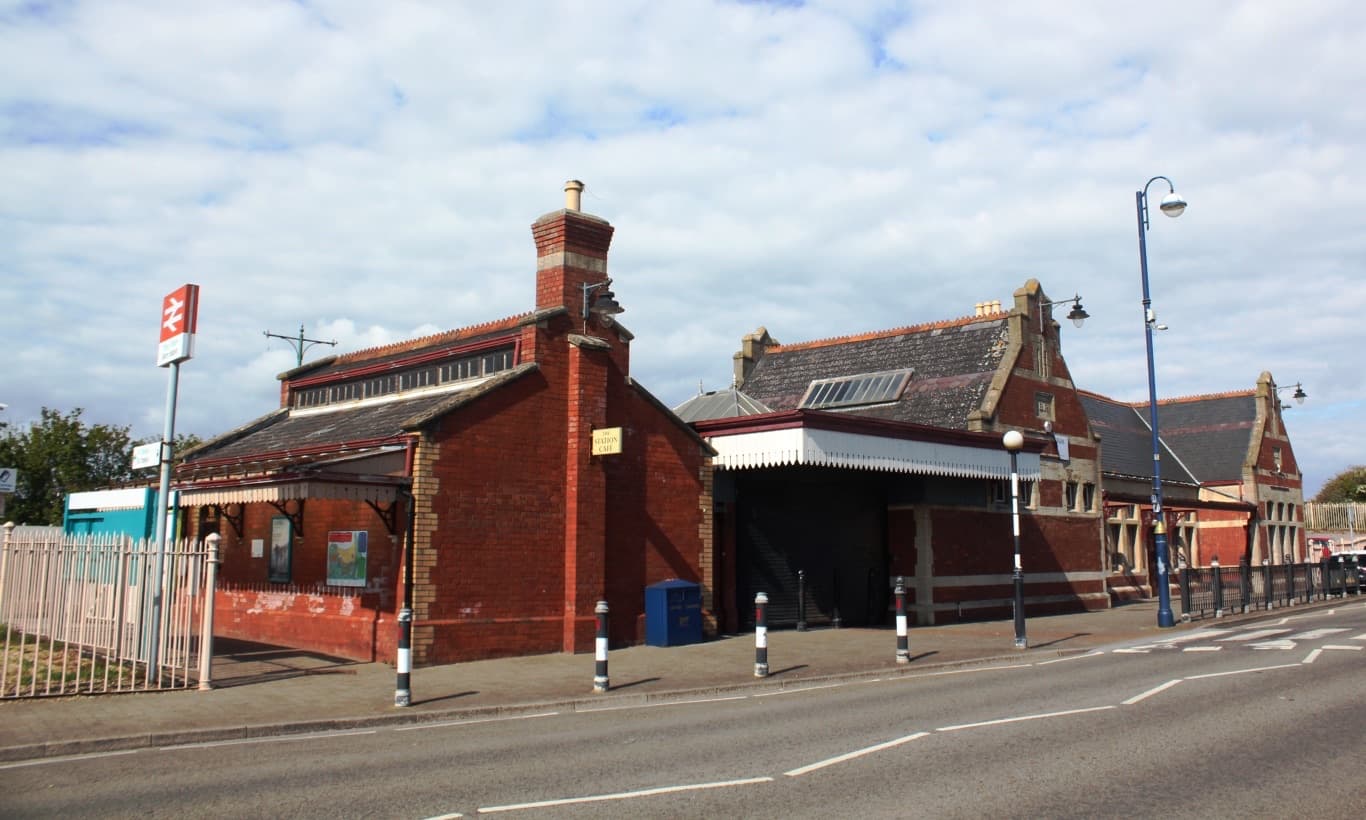 Red-brick station buildings beside a quiet road
