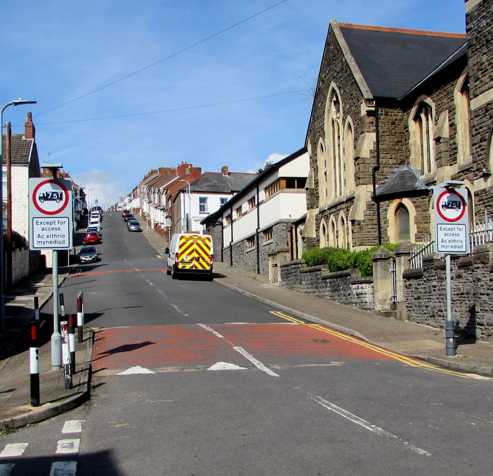 A steep street of terraced houses climbing away from a stone chapel