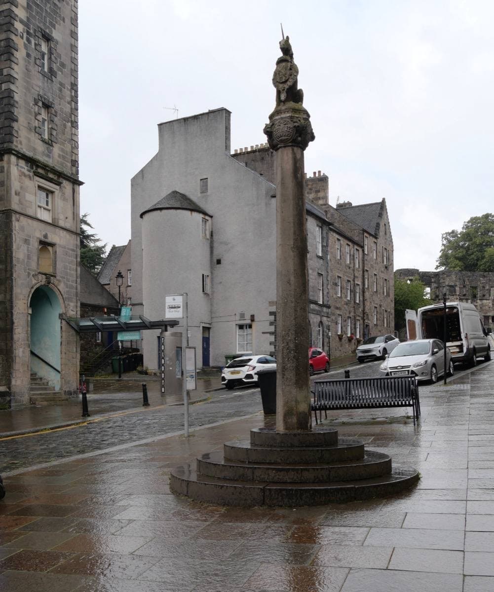 A stone market cross in a cobbled old-town street