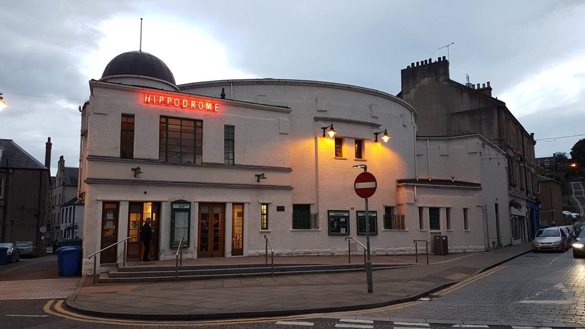 A small white picture house lit up at dusk