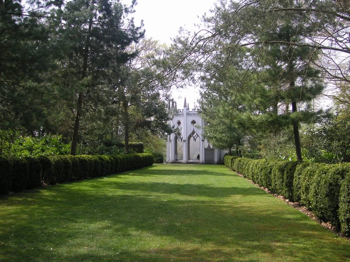 A landscape garden with a lake and a small Gothic temple among trees