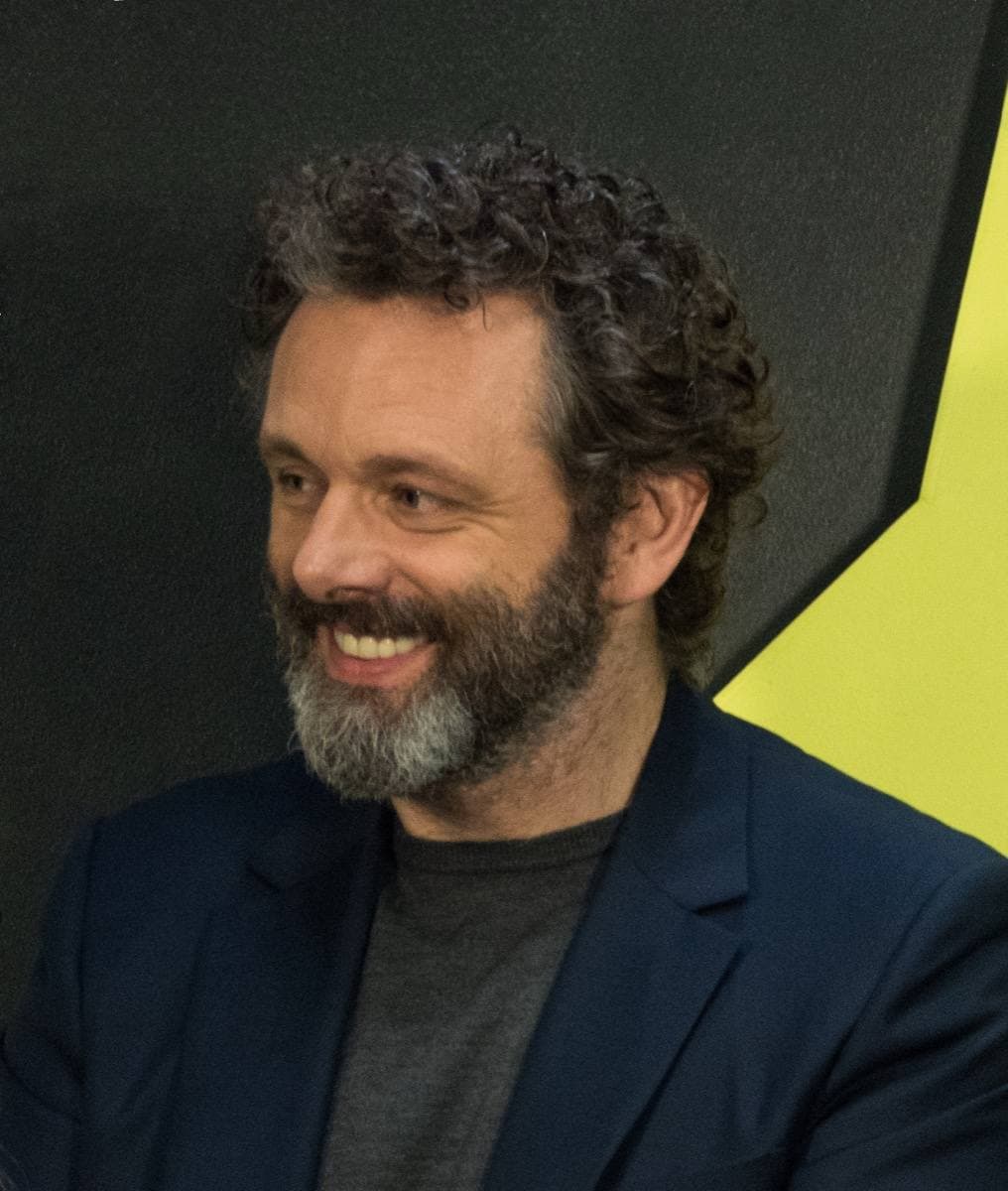 A man with swept-back fair hair smiling at a panel table
