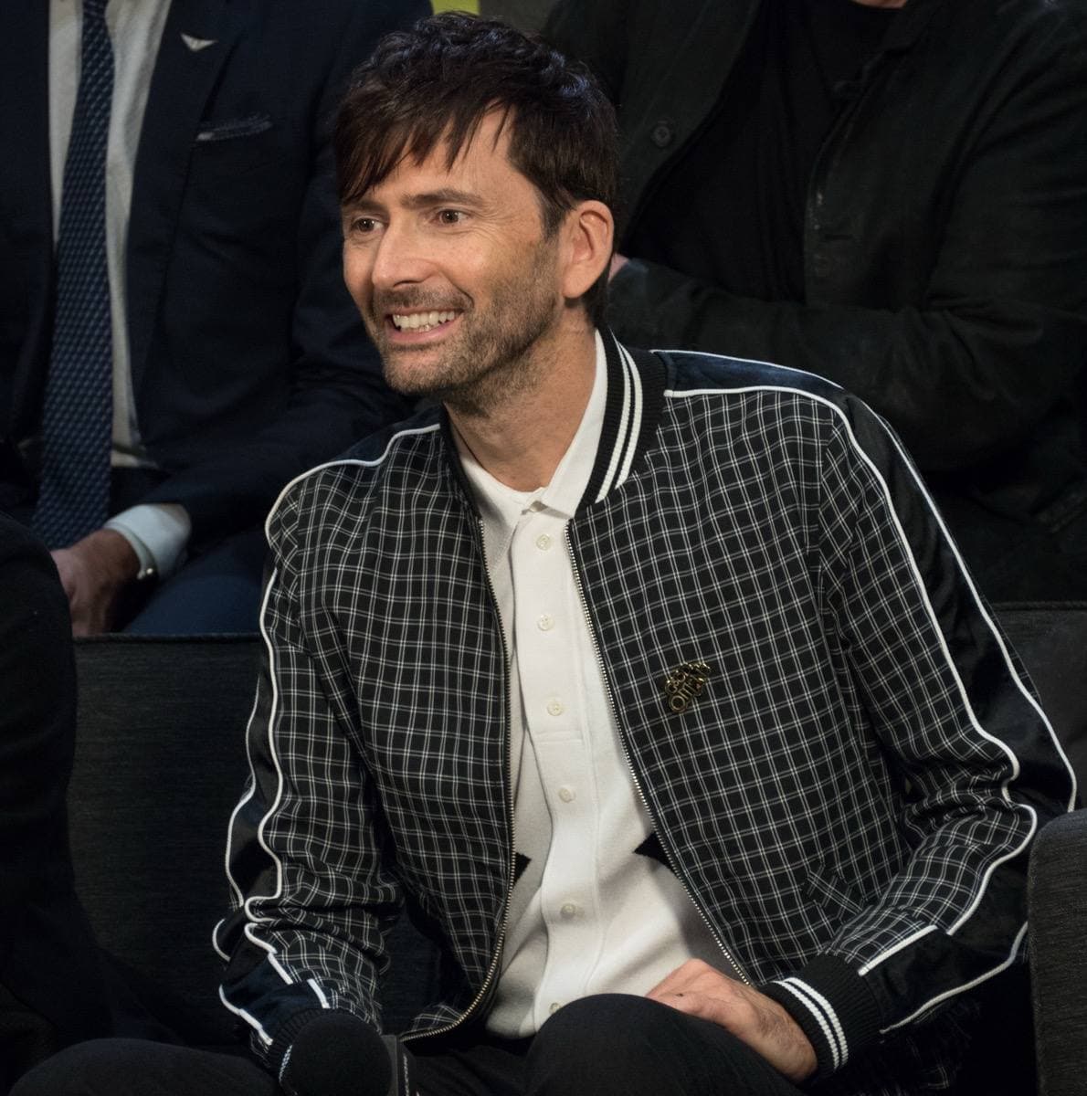 A man with dark hair and stubble speaking at a panel table