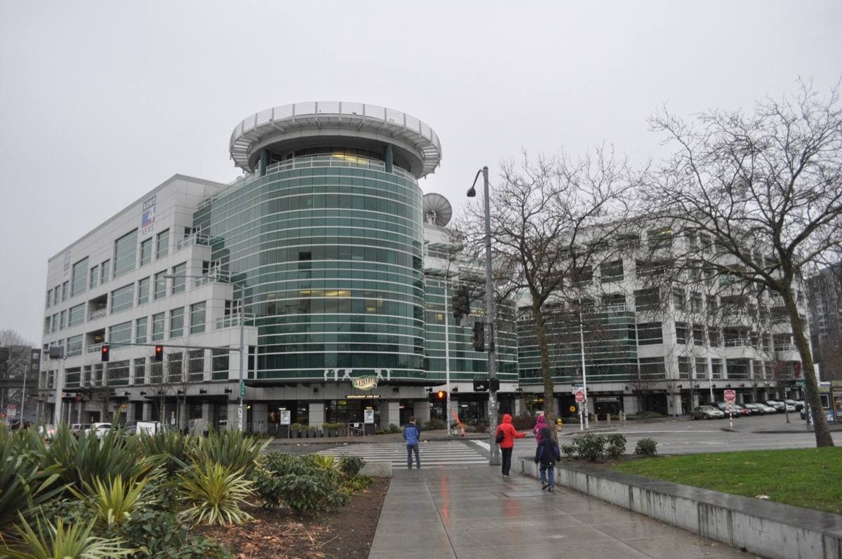 A curved glass and metal office building on a Seattle street corner