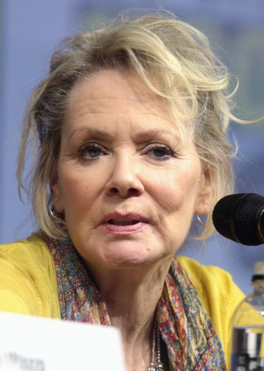 A smiling woman with short blonde hair speaking into a microphone