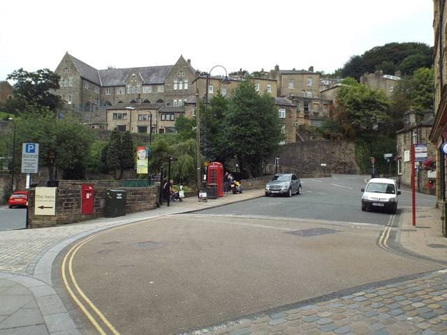 A sloping town square of stone buildings with a red phone box and a postbox