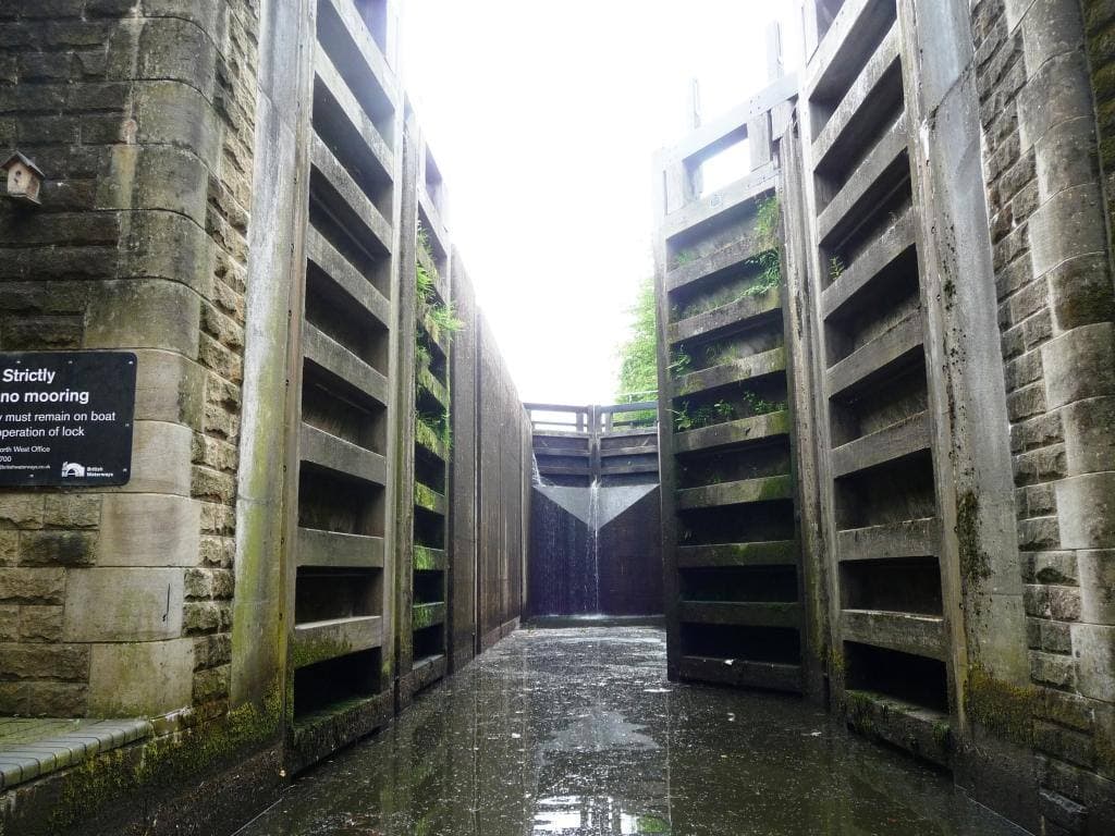 A narrow lock chamber between towering stone walls and tall wooden gates