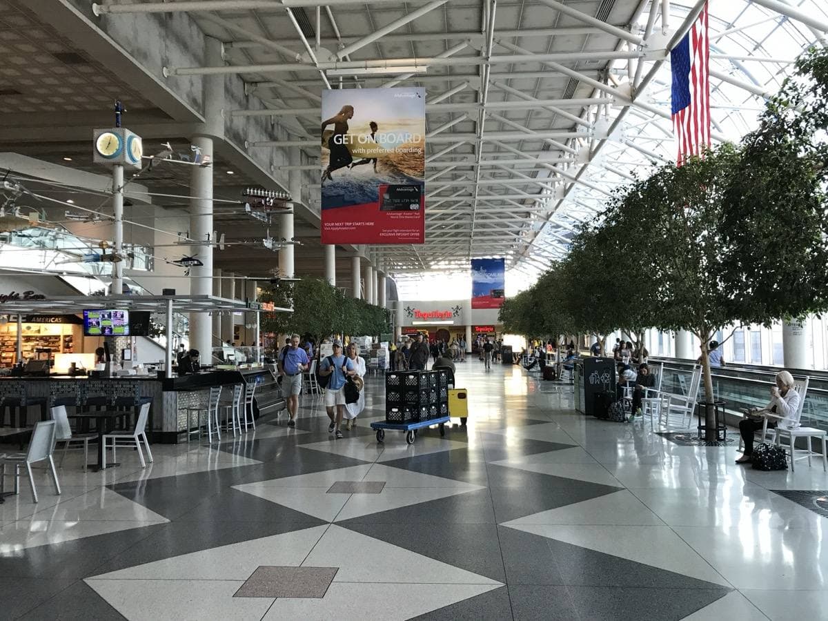 A bright airport atrium with rocking chairs and a glass roof