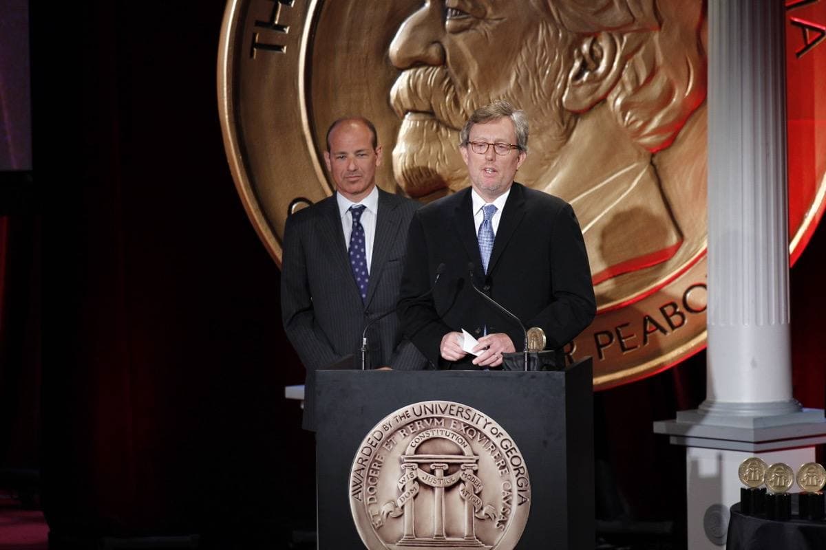 Two men in suits at a lectern holding a Peabody award