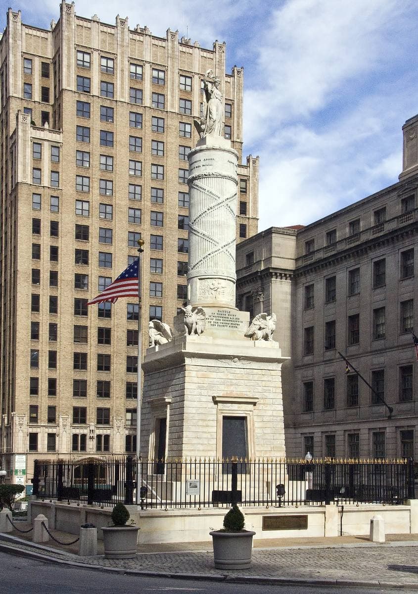A white marble column monument in a city square