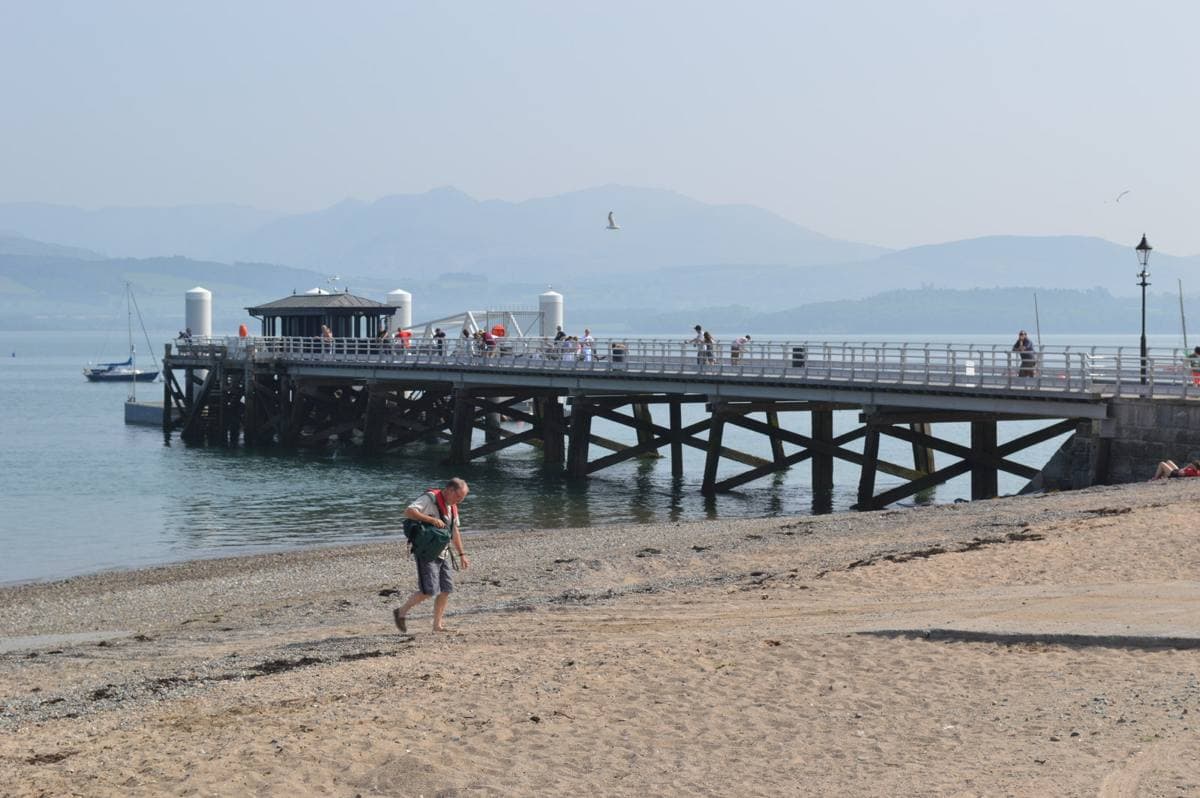 A long pier running out over calm water towards mountains