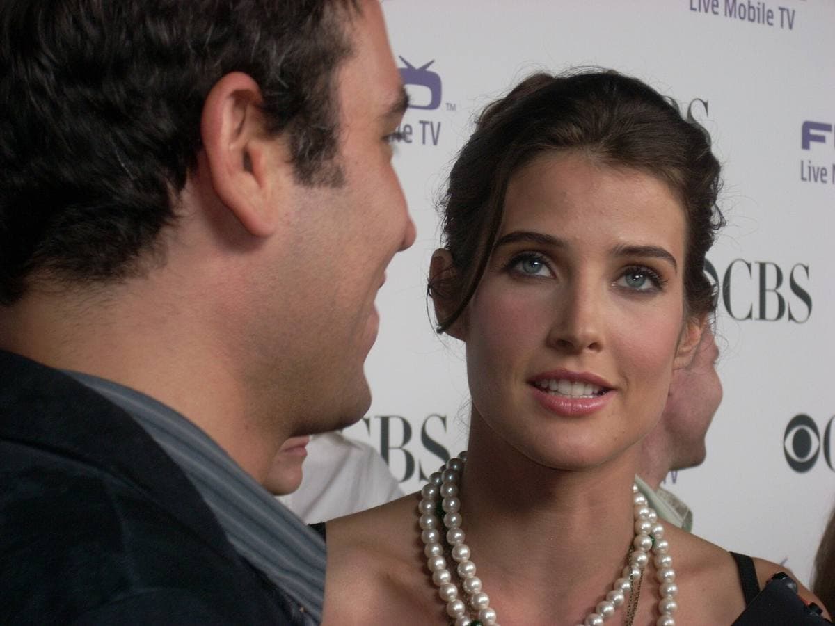 A dark-haired man and a woman with long dark hair smiling side by side