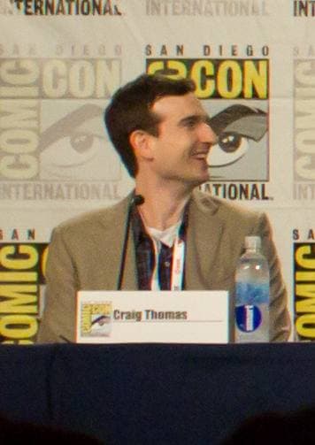 A man with short dark hair at a panel table
