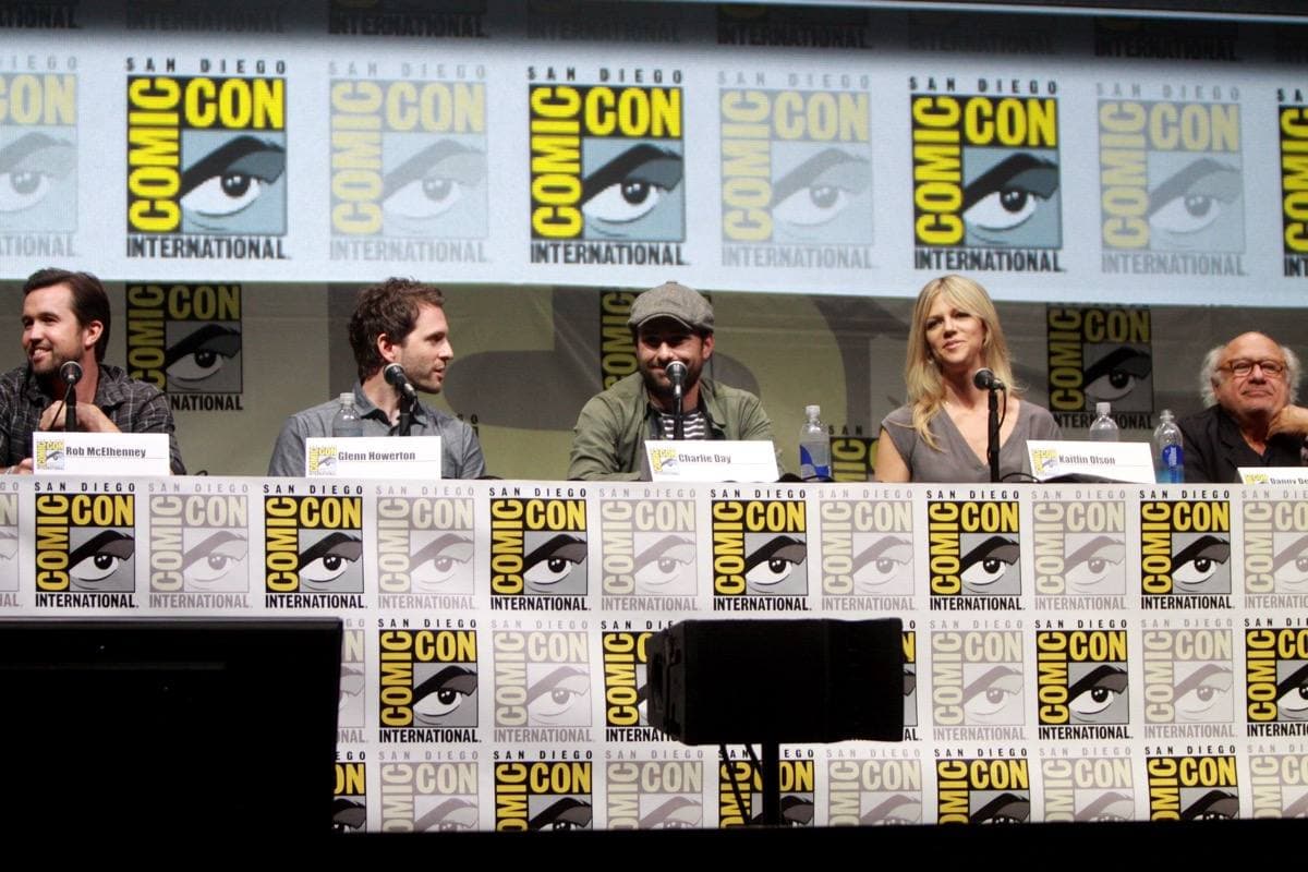 Five cast members seated at a panel table in front of microphones