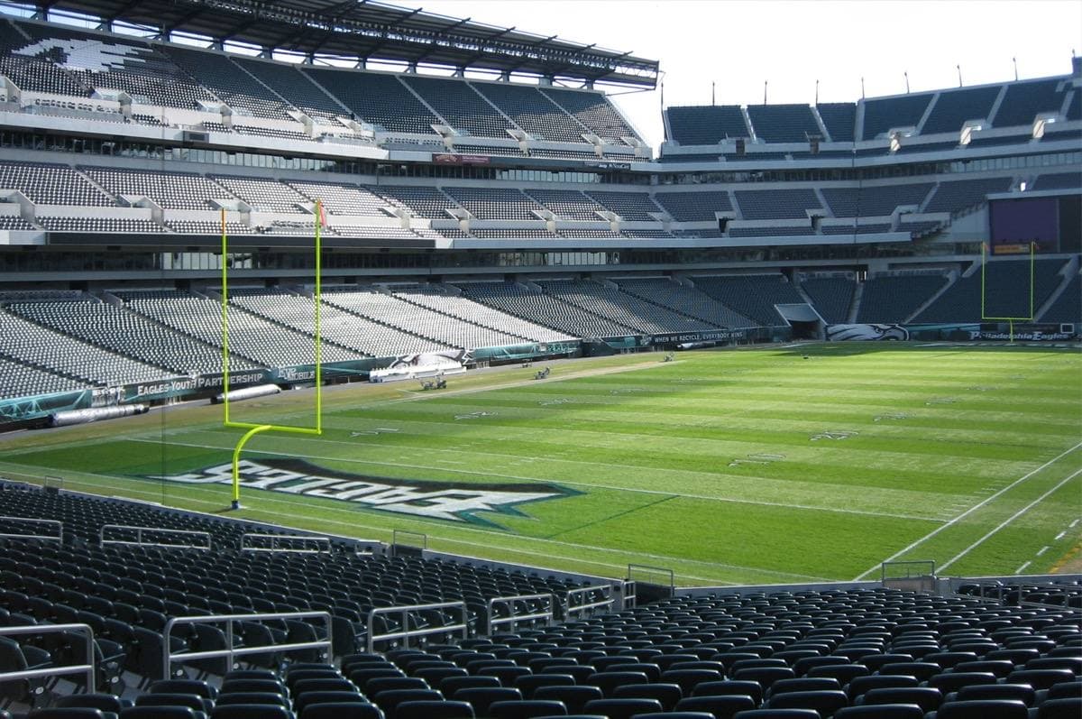 The pitch and stands of a large football stadium seen from behind a goalpost
