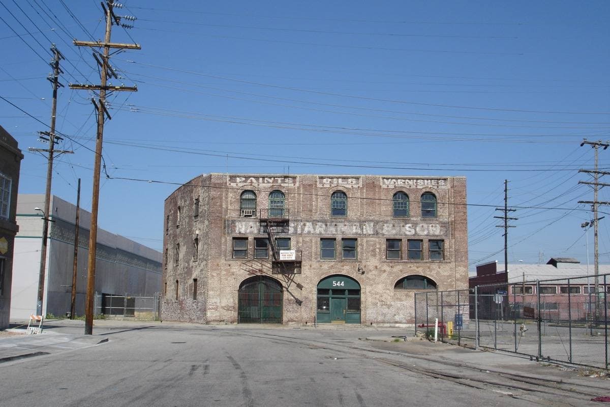 A weathered brick warehouse with a faded painted sign on a wide street corner