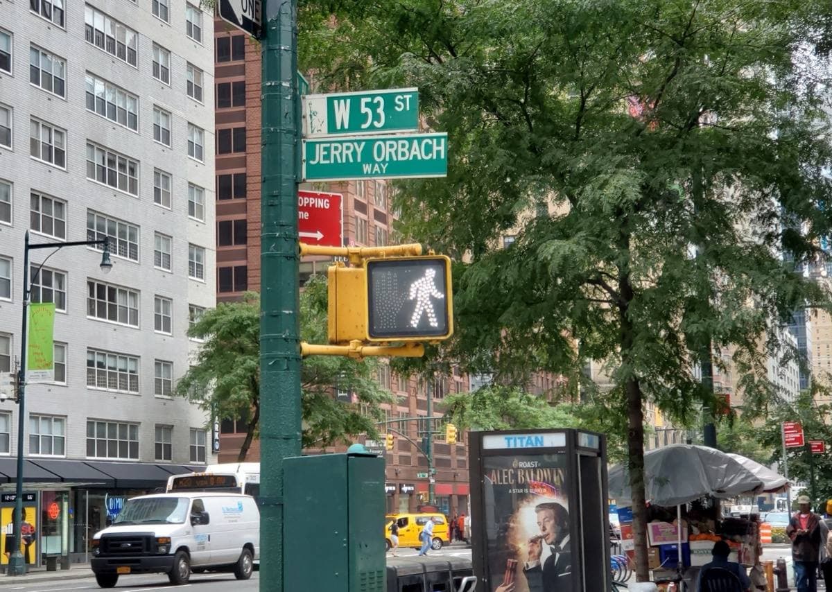 A green New York street sign reading Jerry Orbach Way on a traffic-light pole