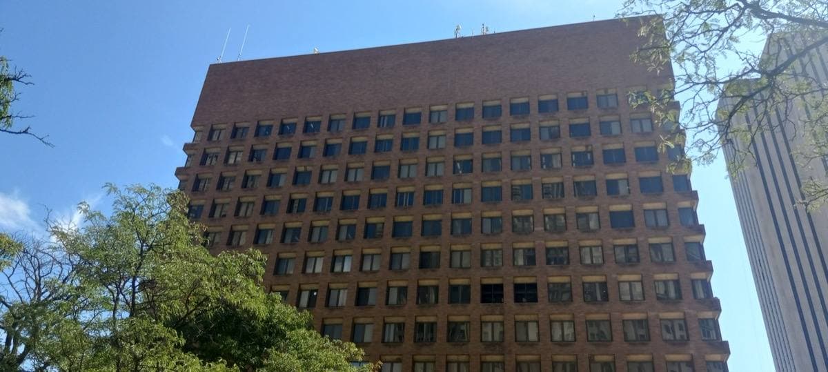 A tall brick-red cube of a building over an open plaza